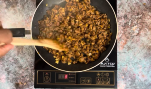 Once the ground beef is browned, add the can of Rotel diced tomatoes with green chilies, salt, and pepper. Stir well to combine.