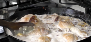 Add the cooked chicken drumsticks back to the skillet and toss them in the creamy garlic sauce until fully coated.